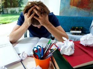 Verzweifelter Schüler über Schulbüchern