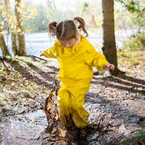 Kind springt in eine Matschpfütze