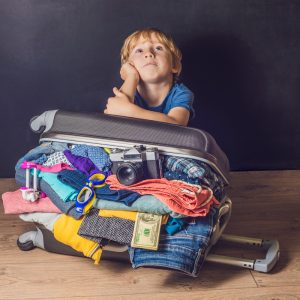 Junger vor gepacktem Koffer