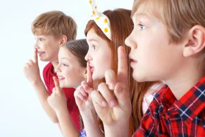 Kinder halten sich die Finger auf den Mund