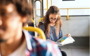 Mädchen liest eine Sprachzeitung im Bus
